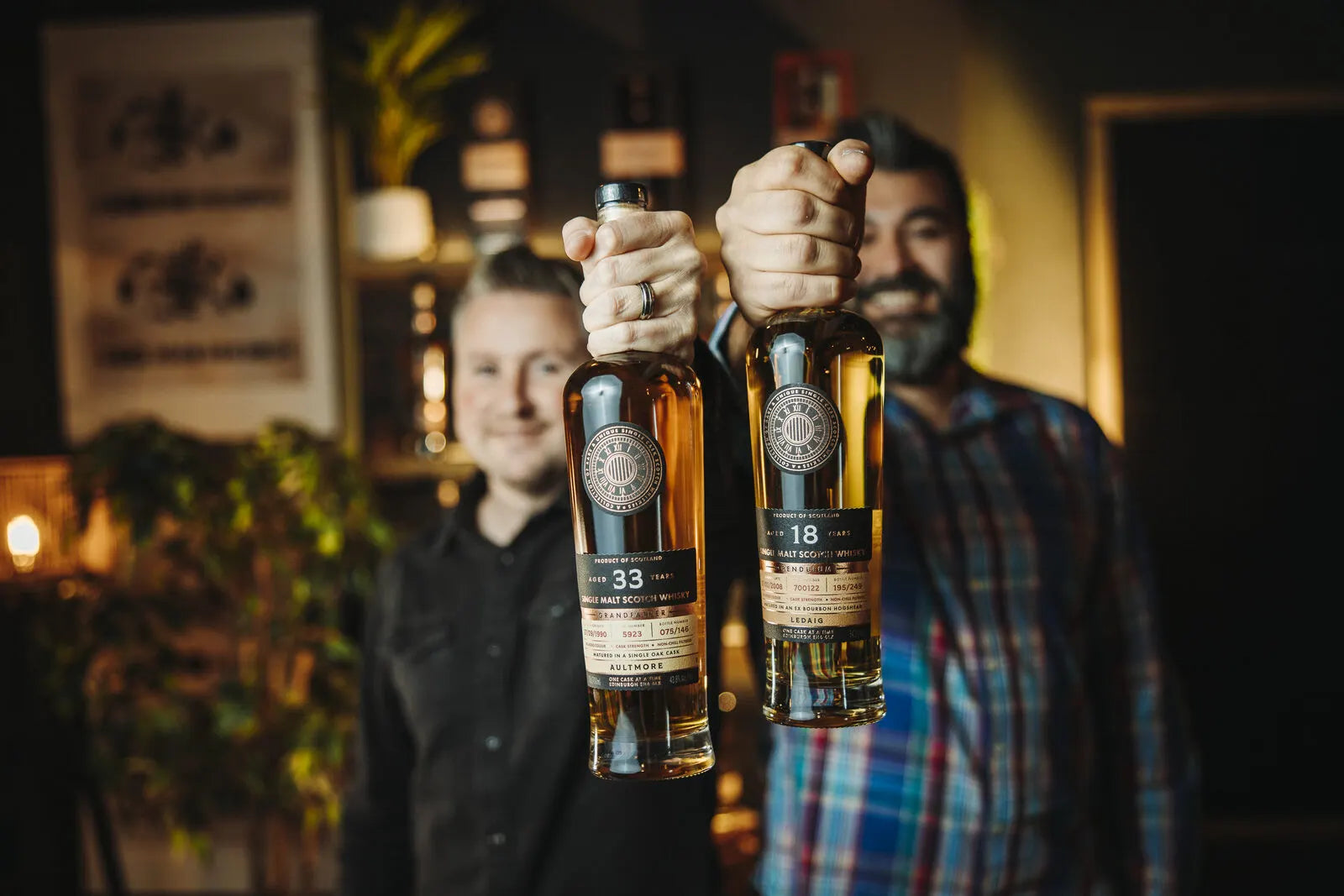 Russell and Jamie, each holding up a bottle of One Cask at a Time